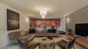 Ein modernes Wohnzimmer mit einer Sofagarnitur, einem Couchtisch und einem Fernseher.