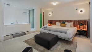 Ein modernes Schlafzimmer mit einem großen Bett, einem separaten Badezimmer und einer kleinen Sitzecke.