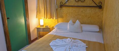 Une chambre d’hôtel comprenant un lit, une table de chevet avec une lampe et un élément décoratif fixé au mur.