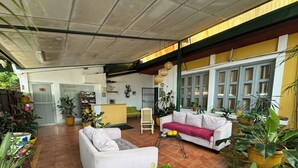 A spacious indoor area with a reception desk, a white sofa, and various potted plants. - La Posadita de Bolonia (Managua)