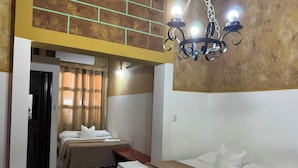 A hotel room with two beds, a chandelier, and a view of the outside through a window with curtains. - La Posadita de Bolonia (Managua)
