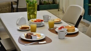 A breakfast table with plates of toast, pancakes, eggs, and a drink. - La Posadita de Bolonia (Managua)