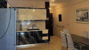 A modern kitchen with a marble countertop, a built-in oven, and a dining area with patterned chairs. - Apartment with two bedrooms, one with a double bed and one with two beds (Saranda)