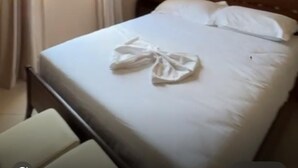 A neatly made bed with white linens, a wooden headboard, and a window with curtains. - Apartment with two bedrooms, one with a double bed and one with two beds (Saranda)