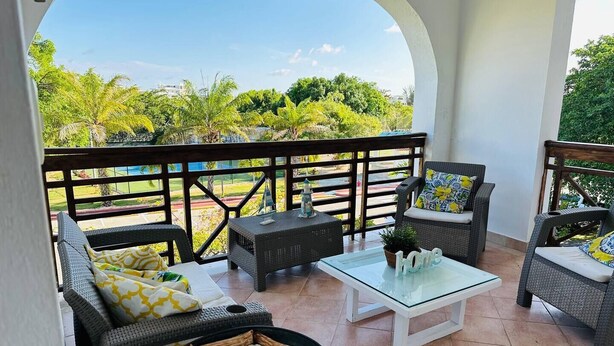 A covered patio with wicker furniture, a glass coffee table, and a small fire pit. - Sunrise Family Hub (Punta Cana)