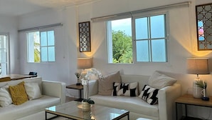 A spacious living room with a white sofa, a glass coffee table, and a ceiling fan. - Sunrise Family Hub (Punta Cana)