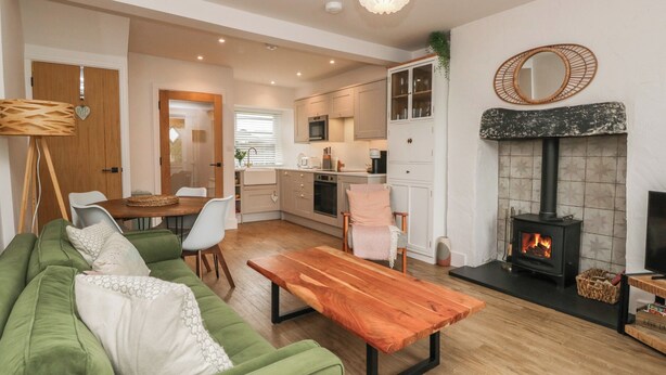 A modern living room with a green sofa, wooden coffee table, and a fireplace. - Wansfell Nook (Ambleside)