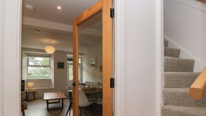 A modern interior with a wooden door leading to a dining area and a staircase. - Wansfell Nook (Ambleside)