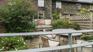 A stone house with a garden patio, outdoor seating, and a view of neighboring houses. - Wansfell Nook (Ambleside)
