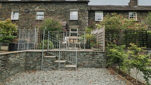 A stone house with a small garden, a metal fence, and a gravel pathway. - Wansfell Nook (Ambleside)