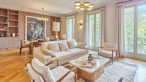 A spacious living room with a sofa, armchairs, a coffee table, and a dining area.