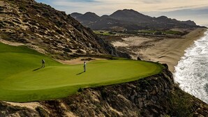Un campo de golf con vistas al océano y a las montañas.