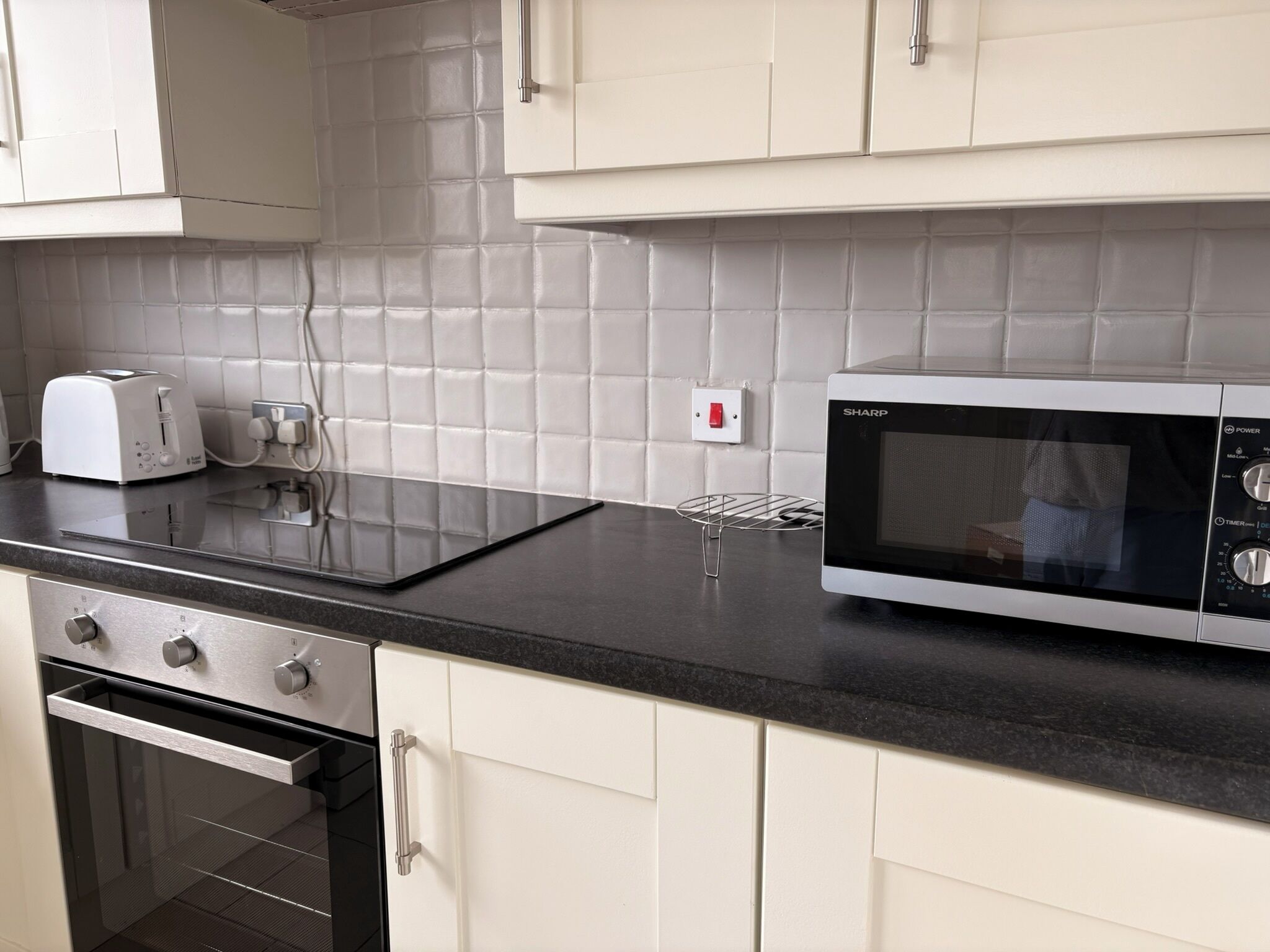 Una cucina con un tostapane, un forno a microonde e un fornello.
