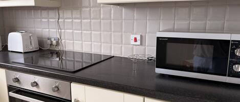 Una cucina con un tostapane, un forno a microonde e un fornello.