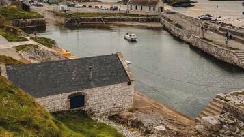A coastal town with stone buildings, a harbor, and a boat.