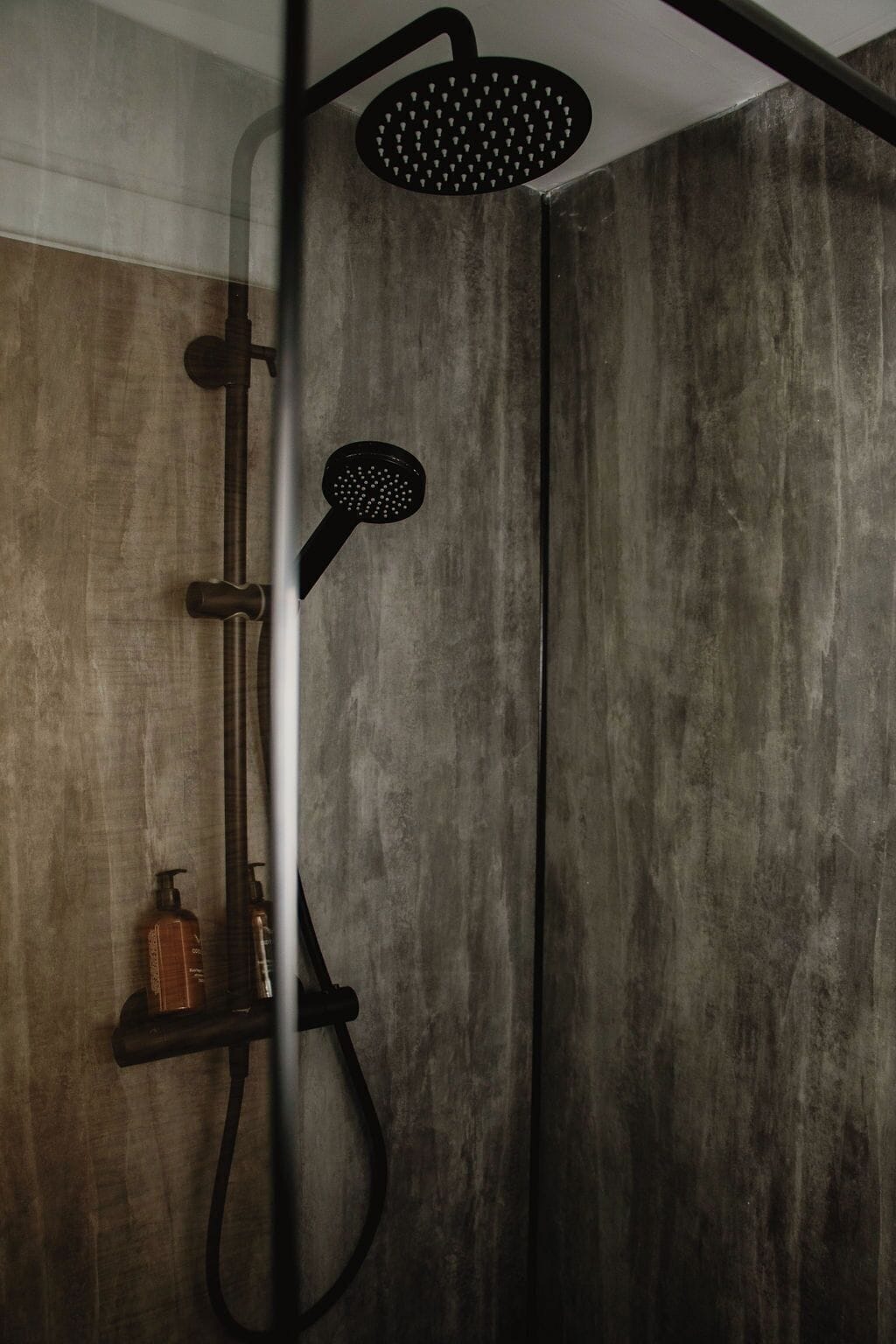 Una ducha con cabezal de ducha de mano y cabezal de lluvia instalado en la pared.