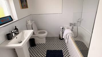 A compact bathroom with a toilet, sink, and shower.