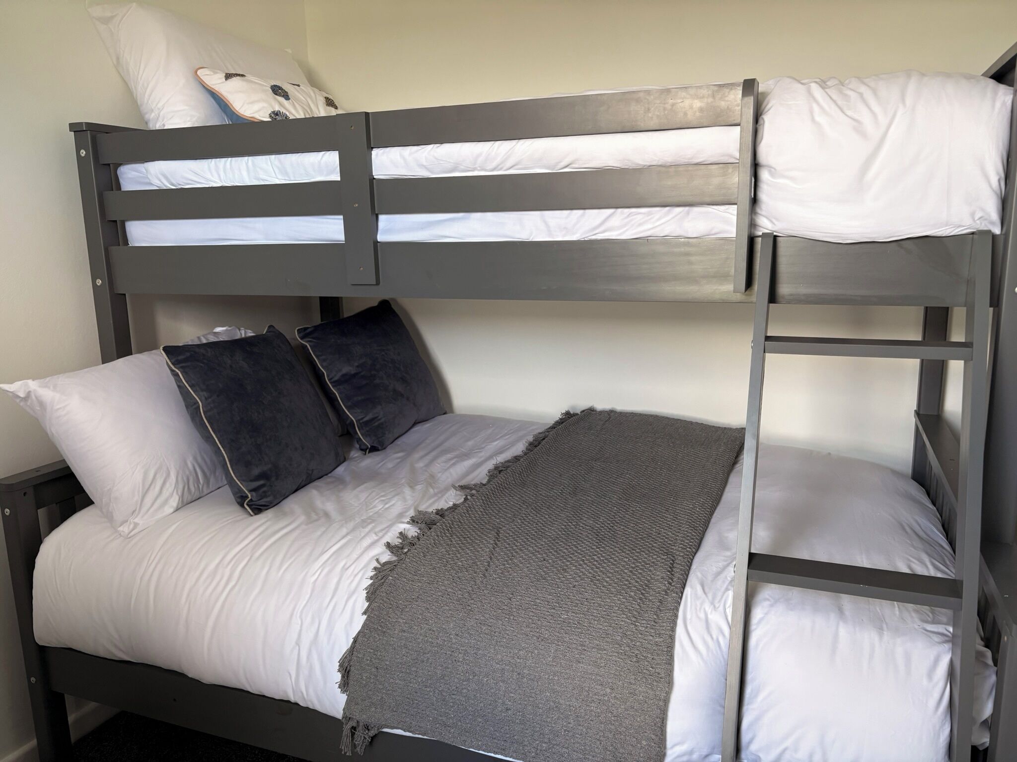 A bunk bed with white bedding and two pillows.