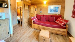 L’intérieur d’un chalet en bois chaleureux, avec un canapé rouge, des meubles en bois et une petite table.