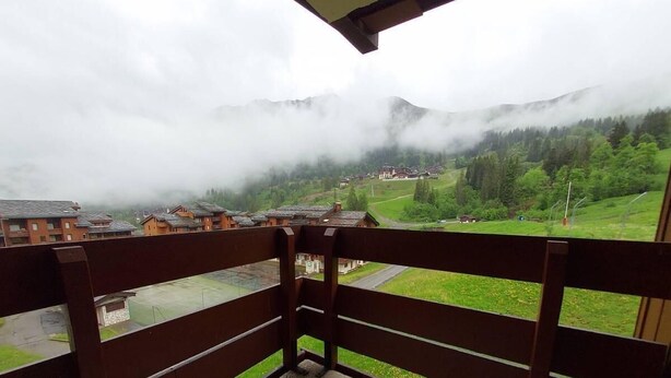 Un balcon offrant une vue sur un paysage montagneux et un village situé en contrebas.