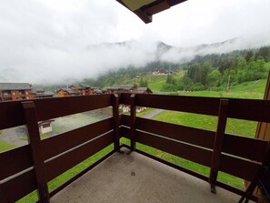 Un balcon offrant une vue sur un paysage montagneux et un village situé en contrebas.