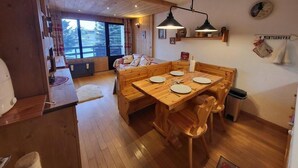 Un comedor acogedor de madera con una mesa dispuesta para cuatro, bancos de madera y una ventana con vistas a árboles.