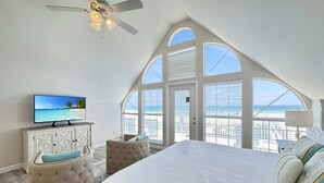 Ein Schlafzimmer mit einem großen Bett, einem Fernseher und Blick auf den Strand.