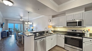 A modern kitchen with white cabinets, stainless steel appliances, and a wooden floor.
