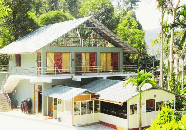 Un bâtiment à deux étages, doté d’un toit plat, d’un balcon à l’étage supérieur et d’une petite structure attenante sur laquelle est apposée une enseigne.