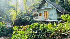 A house with a balcony, surrounded by lush greenery and a river. - Falling Water Resort by Travent Mug (Sakleshpur)
