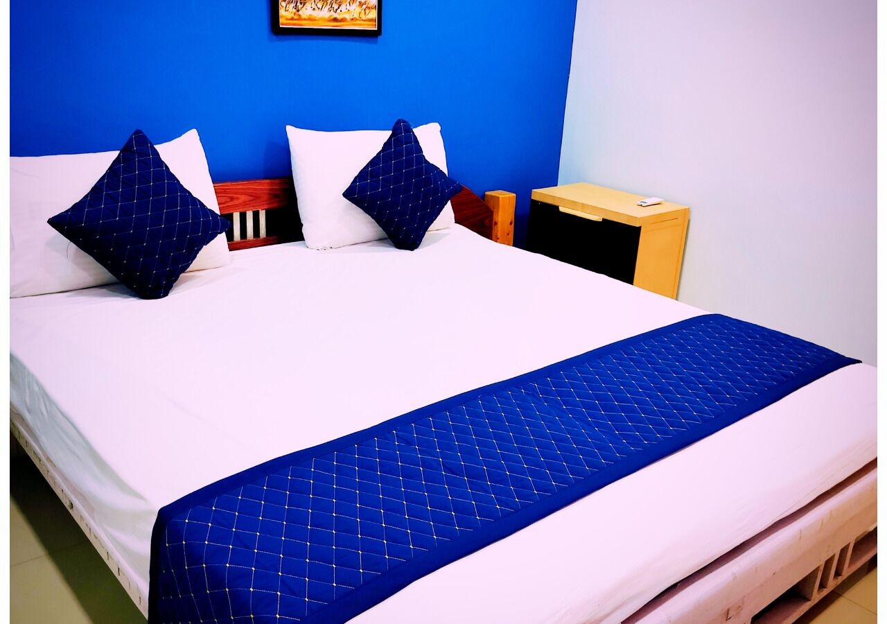 A bed with a blue quilt, white pillows, and a wooden headboard.