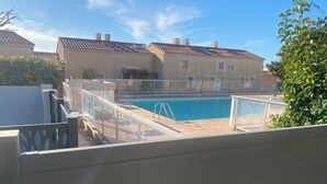 Piscina com balaustrada de vidro, cercada por uma grade.
