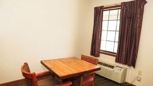 A small room with a wooden table and two chairs, a window with patterned curtains, and a wall-mounted air conditioner. -  Hotel Deerfield Inn & Suites Acworth Atlanta (Acworth)
