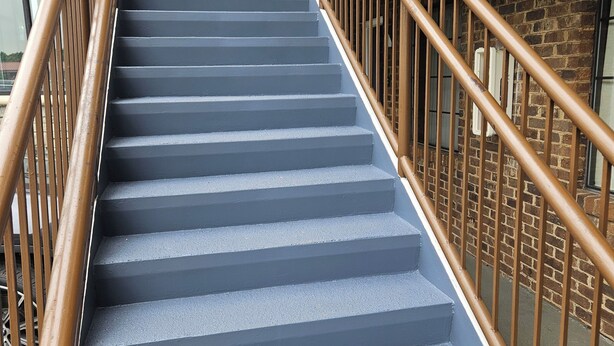A staircase with metal railings and a brick wall. -  Hotel Deerfield Inn & Suites Acworth Atlanta (Acworth)