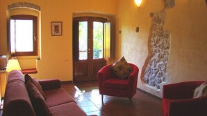Ein Wohnzimmer mit einem roten Sofa, einem roten Sessel und einer Steinskulptur an der Wand.