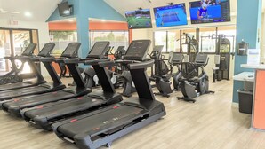 A gym with multiple treadmills, exercise bikes, and a television displaying sports events. - NEW Modern 3bd Home in Palm Springs,PGA Country Club the Ultimate Retreat (Cathedral City)