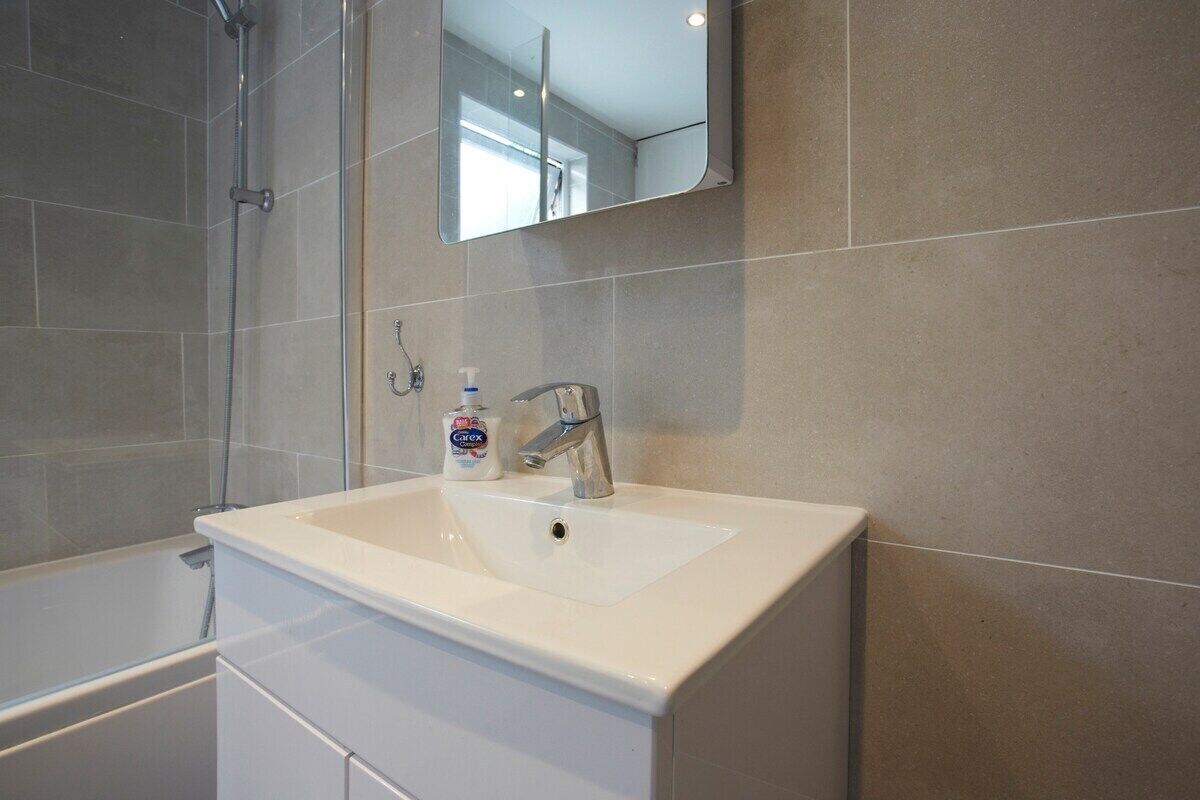 Une salle de bain avec un lavabo blanc, un miroir et une douche.