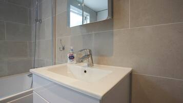 Une salle de bain avec un lavabo blanc, un miroir et une douche.