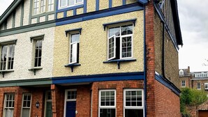 Ein zweistöckiges Haus im traditionellen Stil mit einer Kombination aus Ziegel- und Putzfassade sowie einem markanten Schornstein.