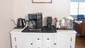 A kitchen counter with a coffee maker, a Keurig, and a coffee pot. There is a framed sign on the wall that reads "coffee bar".