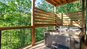 A hot tub on a wooden deck with a view of a forest. - 5BR Retreat Near Dollywood, w Hot Tub & Game Room! (Pigeon Forge)