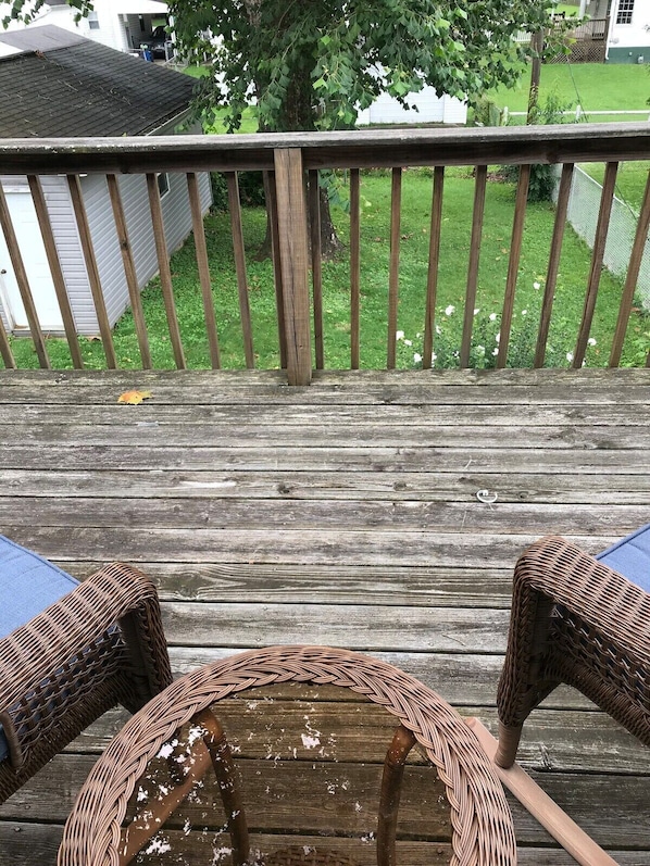A wooden deck with two wicker chairs and a small round table.