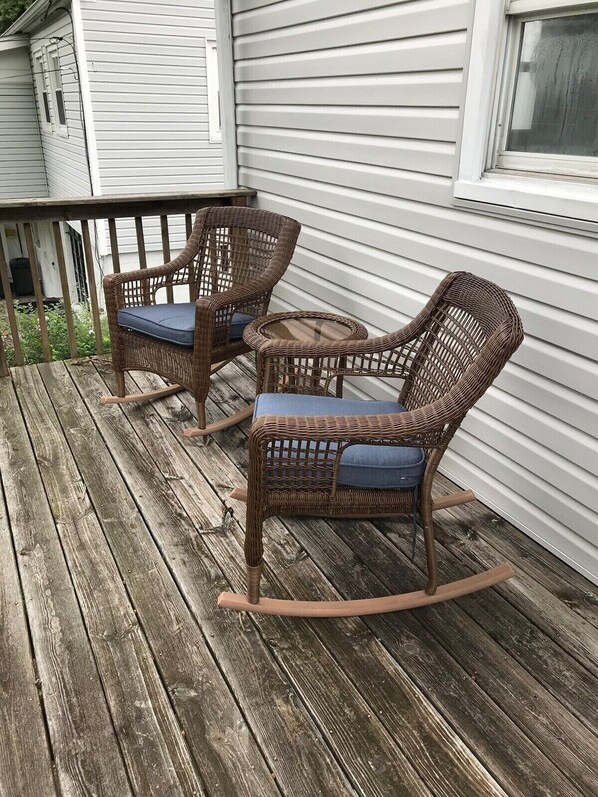 A wooden deck with wicker rocking chairs and a small table.