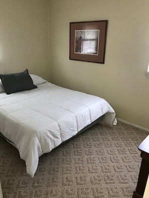 A bedroom with a bed, a framed picture on the wall, and a carpeted floor. - Kanawha City Home (Charleston)