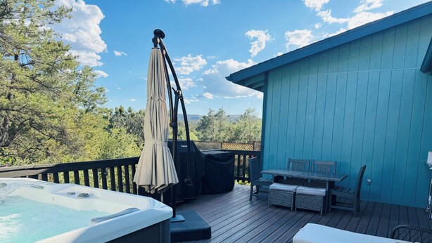 Una terraza de madera con jacuzzi, mobiliario exterior y una zona cubierta.