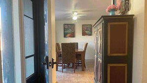 Un comedor con una mesa y sillas, un ventilador de techo y obras de arte en las paredes.