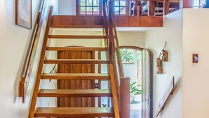 A wooden staircase leading to a second floor with a tiled floor and a ceiling with wooden beams. - Villaggio Dei Pini (Ubatuba)