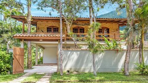 A two-story building with a brick facade and a balcony. - Villaggio Dei Pini (Ubatuba)