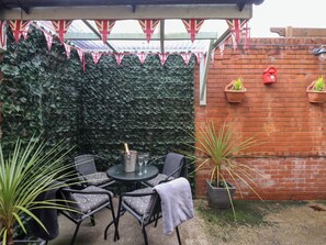 A patio with a table and chairs, a potted plant, and a brick wall. - Postmans Lodge (Middlesbrough)