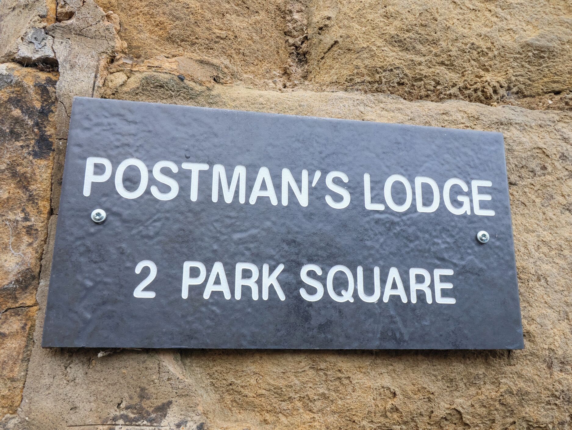 A sign for Postman's Lodge at 2 Park Square.